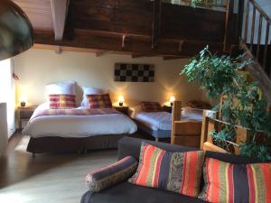 ベス・エ・サンタナステーズにあるAuberge de la Petite Ferme, Super-Besse Est, The Originals Relaisのベッド2台とソファのあるリビングルーム