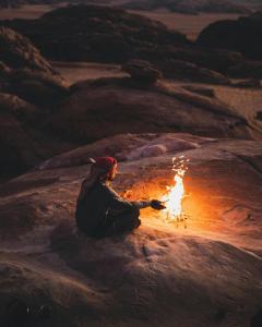 a person sitting around a fire in the desert at Wadi Rum Bedouin Heart in Wadi Rum