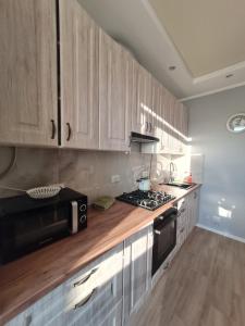 cocina con armarios de madera y microondas negro en Апартаменти в центрі, en Lutsk