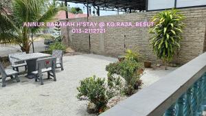 a patio with a table and chairs next to a brick wall at Homestay Annur Barakah in Kampung Raja