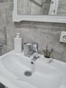 Un fregadero blanco con una licuadora y flores encima. en Апартаменти в центрі, en Lutsk