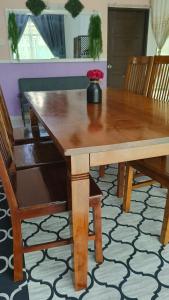 a wooden dining room table with a vase of flowers on it at Homestay Annur Barakah in Kampung Raja