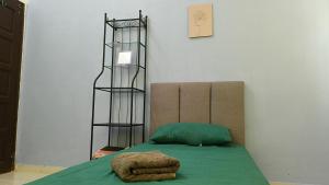 a room with a bed with a green blanket and a shelf at Homestay Annur Barakah in Kampung Raja