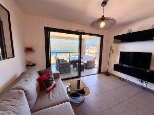a living room with a couch and a flat screen tv at Appartement neuf tout confort en bord de mer in Propriano