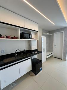 Una cocina con gabinetes blancos y una encimera negra. en Home Studio, en Sobral