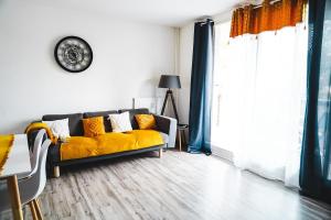a living room with a yellow couch and a clock at Panorama Méditerranéen Vue exceptionnelle sur le Mont Caume et Faron 3 chambres 69m2 in Toulon