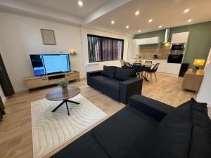 a living room with a black couch and a kitchen at Family Apparts Criel in Criel-sur-Mer