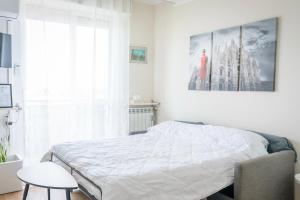 a white bedroom with a bed and a large window at Eleventh Floor apartment Milano in Cinisello Balsamo
