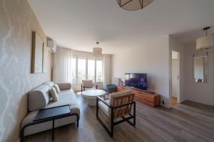 un soggiorno con un divano e una TV di Art de Recevoir - Prestige & Vue Panoramique sur Saône - Parking Privé T3 Appartement Climatisé a Fontaines-sur-Saône