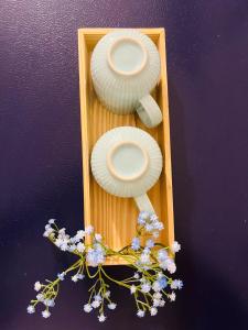 una bandeja de madera con dos platos blancos y flores en Casa Symphony- Hill View Spacious Studio in Baner-Pashan, en Pune
