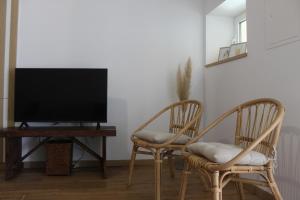 a living room with two chairs and a flat screen tv at Casa do Caseiro, São Silvestre in São Silvestre
