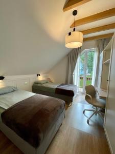 une chambre avec deux lits, un bureau et une chaise dans l'établissement Alpennelke family apartments, à Bohinjska Bela