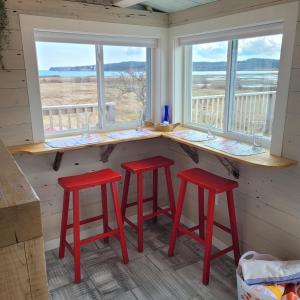 a kitchen with two red stools and two windows at Sunrise by the Sea in Lubec +39 photos