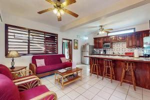 a living room with a red couch and a kitchen at Plumeria @ Caribe Island in San Pedro