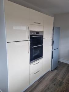 Una cocina con gabinetes blancos y un refrigerador. en Moorefield Villa Newbridge, en Newbridge 25 fotos más