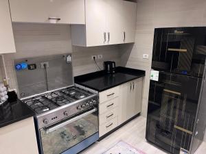 a kitchen with a stove and a refrigerator at A Luxury Hotel Appartment at NEW GIZA Imperial Compound قريبة جدا للمتحف المصري الجديد in Abū Rawwāsh
