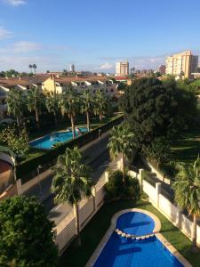 アリカンテにあるCanaima Alicanteのヤシの木と建物が並ぶ2つのプールの上からの眺め
