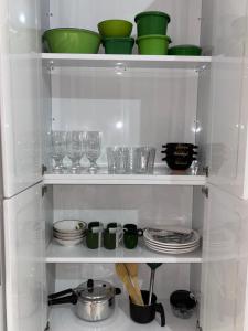 a white shelf with green dishes and glasses on it at Casa Viturino in Tailandia +5 photos