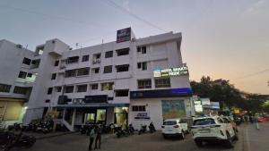 a white building with cars parked in front of it at Hotel Bhakti Pride Panchvati Nashik in Nashik