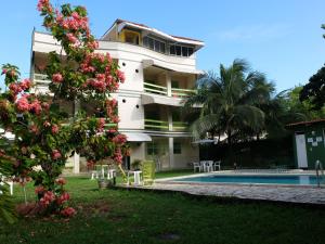 a large white building with a swimming pool and a tree at Cobertura Porto de Galinhas in Porto De Galinhas