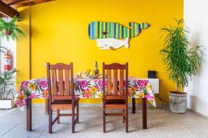 a dining room table with two chairs and a yellow wall at Pousada Maré Cheia in Paraty