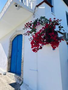 a blue door and a wreath of red flowers on a white building at MAVI KONAK Deluxe Rooms & Suits in Kérynia