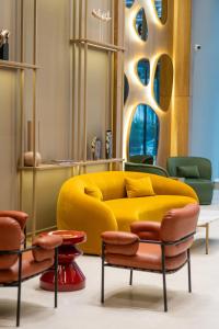 a living room with a yellow couch and chairs at Blue Sky Apart-Hotel Batumi in Batumi +48 photos