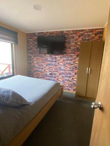 a bedroom with a bed and a brick wall at Apartamentos Natales May 21 in Puerto Natales