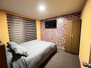 a bedroom with a bed and a brick wall at Apartamentos Natales May 21 in Puerto Natales