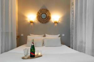 a bottle of beer on a bed with glasses and a mirror at Suite sensuelle et balnéothérapie in Nemours