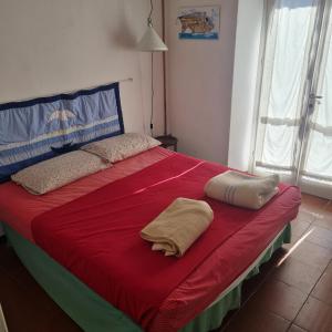 Una cama roja con dos almohadas encima. en Cà Gialla, en Bonassola