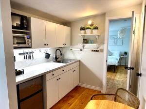 cocina con armarios blancos, fregadero y mesa en NookSide Nest 1 bedroom Upstairs suite King, Queen, Kitchenette, Parking, en Carleton Place