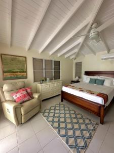 a bedroom with a bed and a chair at Barefoot Luxury Beach Villa in The Valley