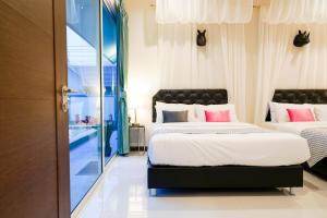 a bedroom with two beds and a sliding glass door at เติมเต็มพลูวิลล่า in Cha Am +27 photos