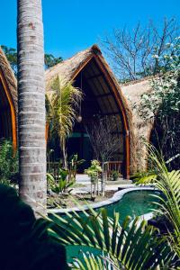 ein Gebäude mit einem Strohdach und einer Palme in der Unterkunft Corabelle Gili Air - Adults Only Boutique Retreat in Gili Air