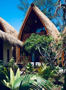 ein Haus mit Strohdach und Pflanzen davor in der Unterkunft Corabelle Gili Air - Adults Only Boutique Retreat in Gili Air