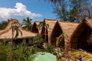 a building with thatched roofs with a green umbrella in front at Corabelle Gili Air in Gili Air