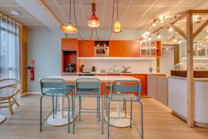 a kitchen with orange cabinets and blue bar stools at Sweetly Saclay Gif-sur-Yvette in Gif-sur-Yvette +34 photos