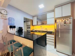 eine Küche mit einem Edelstahlkühlschrank und weißen Schränken in der Unterkunft Apartamento perto de tudo, vista mar, AC quente, Wifi 300mb in Balneário Camboriú + 10 Fotos