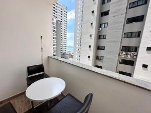 a white table and chairs on a balcony with buildings at Apartamento perto de tudo, vista mar, AC quente, Wifi 300mb in Balneário Camboriú