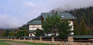 a building with a tree next to a stone wall at Villa Girska Sonata in Mykulychyn +14 photos