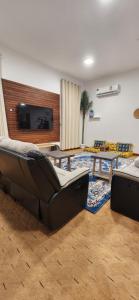 a living room with two couches and a flat screen tv at Private Room in Sur House in Sur
