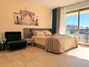 a bedroom with a bed and a chair and a window at Cannes Marina Suite Hôtel Résidence in Mandelieu-la-Napoule