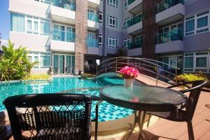 a patio with a table and chairs next to a swimming pool at Calypso Condo Naiharn in Phuket