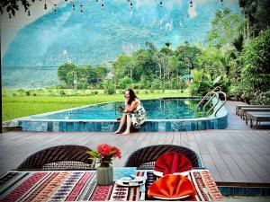 a woman is sitting next to a swimming pool at Mai Chau La Luna in Mai Chau