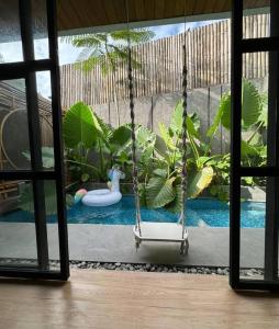 a swing in front of a pool with plants at Akaya Villas Solo in Kemiri