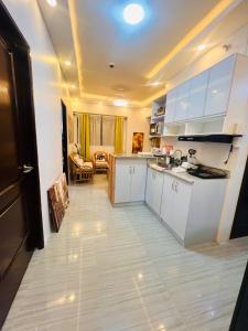 a kitchen with white cabinets and a living room at Mezza Residences in Manila