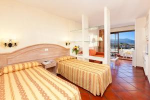 a hotel room with two beds and a balcony at Apartamentos Masaru in Puerto de la Cruz