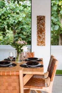 Una mesa de madera con platos y copas de vino encima. en Zendaya Bali Villas, en Denpasar