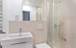Un baño blanco con lavabo y ducha. en Studio in Sutton long stays at least 7 days, en Sutton